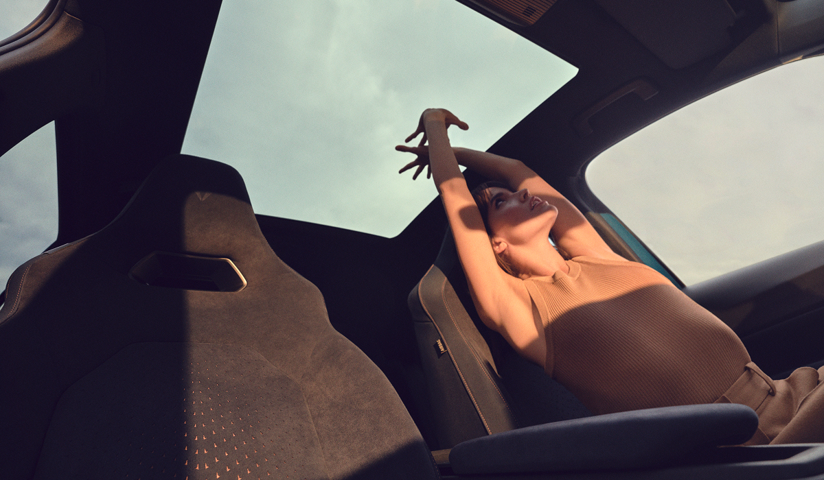 Frau entspannt sich auf dem Beifahrersitz eines CUPRA, Blick durch das Panoramadach in den Himmel